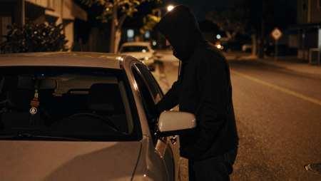 hooded figure stands beside car parked on street at night generated with Z-Image